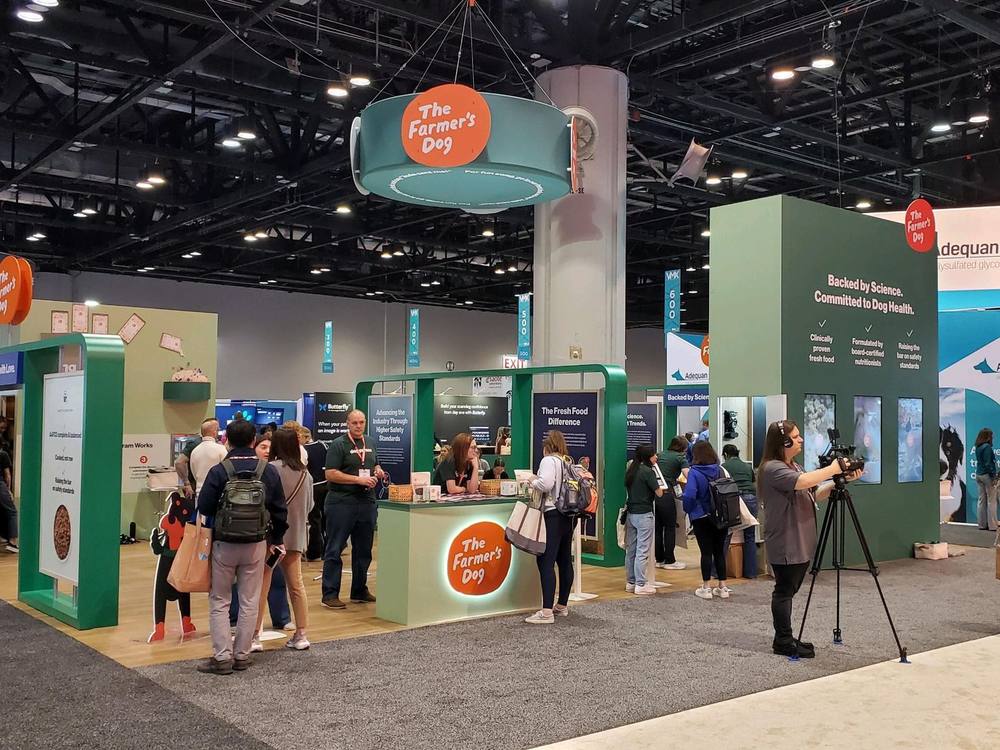 The Farmer's Dog trade show booth at VMX, green architecture with attendees at product stations.
