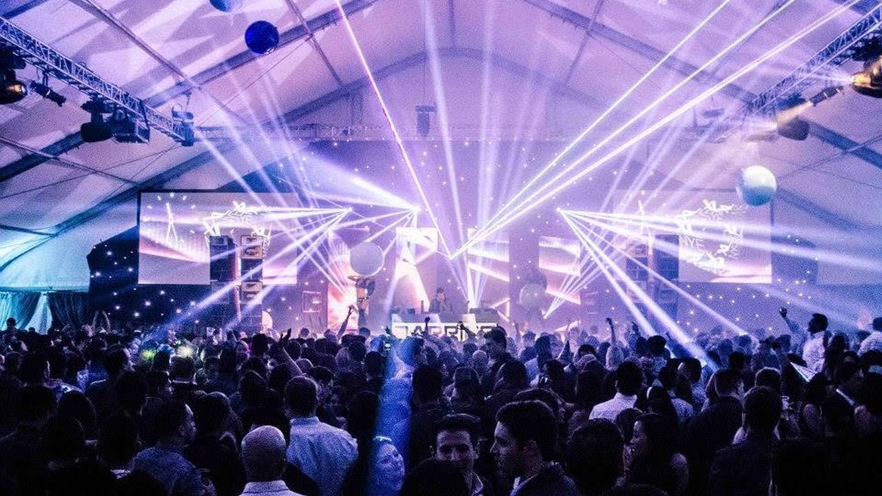 The same tent at capacity on New Year's Eve, lasers over a packed floor.